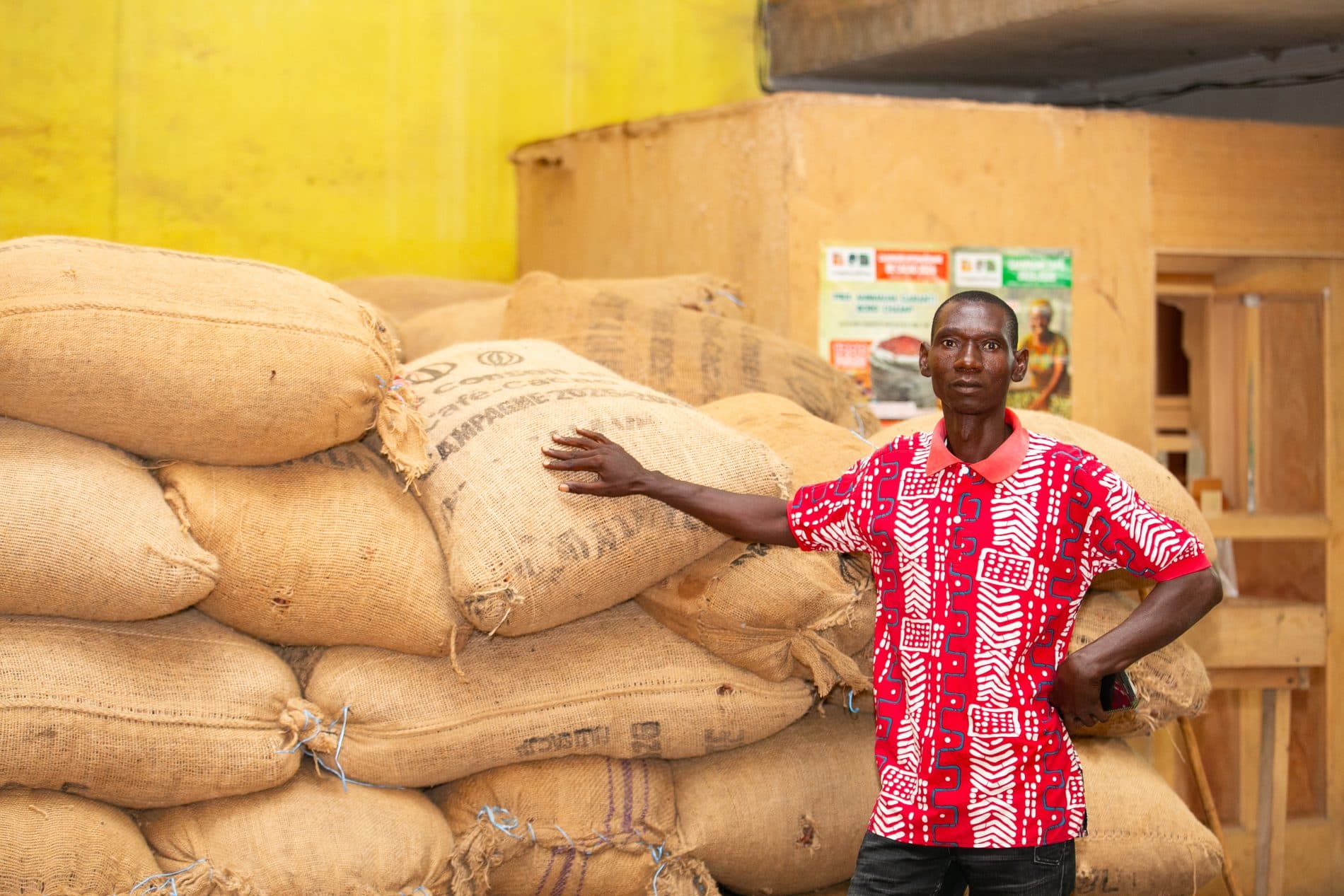 Producteur devant le stock de cacao en sacs de jute, magasin de la coopérative